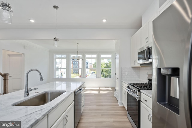 kitchen with sink, white cabinetry, hanging light fixtures, and appliances with stainless steel finishes