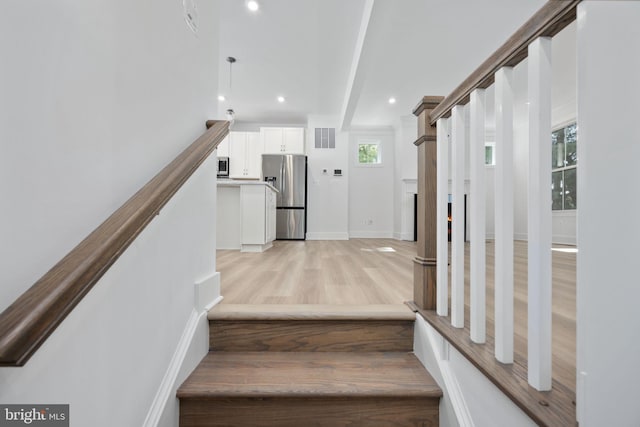 staircase with wood-type flooring, a healthy amount of sunlight, and beamed ceiling