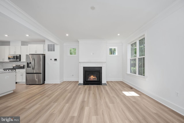 unfurnished living room featuring ornamental molding and light wood-type flooring