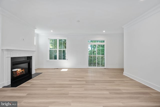 unfurnished living room with light hardwood / wood-style floors, ornamental molding, and a wealth of natural light