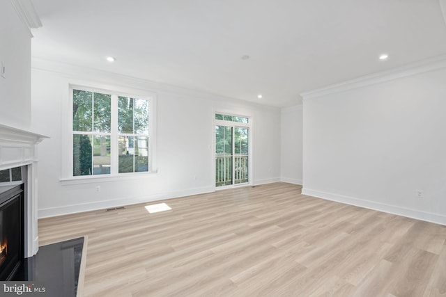 unfurnished living room with ornamental molding, a healthy amount of sunlight, and light wood-type flooring