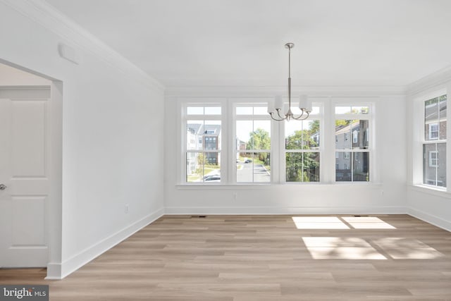 unfurnished dining area featuring light wood-type flooring, crown molding, and a chandelier