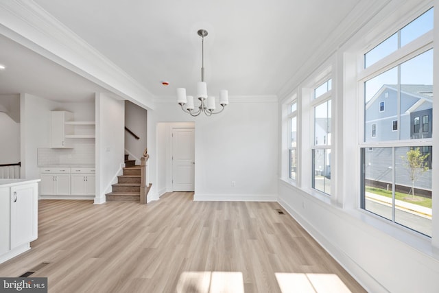 unfurnished dining area featuring light wood-type flooring, a notable chandelier, and crown molding