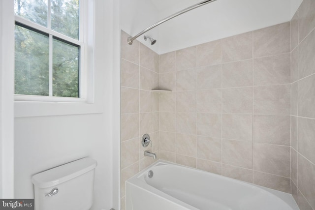 bathroom featuring tiled shower / bath combo and toilet