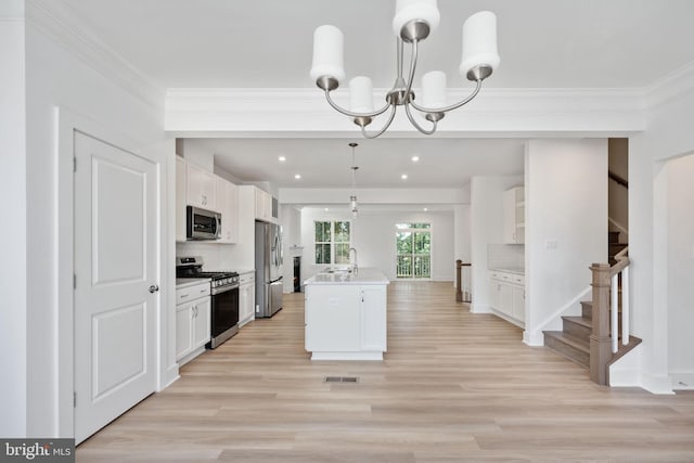 kitchen with stainless steel appliances, an island with sink, pendant lighting, white cabinets, and backsplash