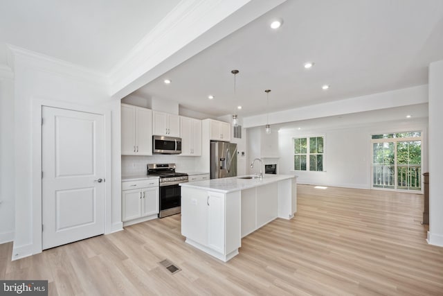 kitchen featuring sink, white cabinetry, hanging light fixtures, a kitchen island with sink, and appliances with stainless steel finishes