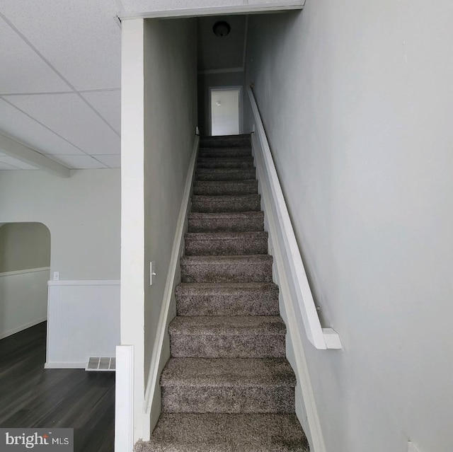 staircase featuring a paneled ceiling and hardwood / wood-style flooring