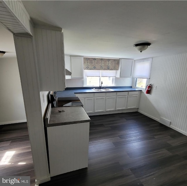 kitchen featuring black range oven, extractor fan, sink, white cabinets, and dark hardwood / wood-style floors