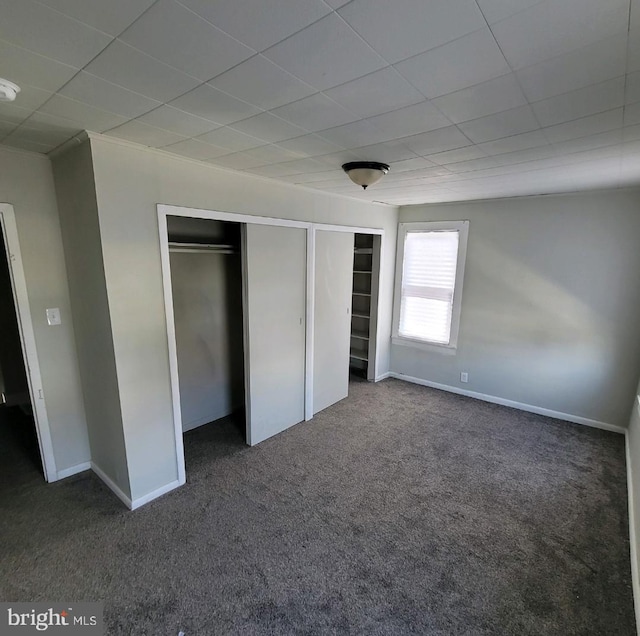 unfurnished bedroom with dark carpet and a closet