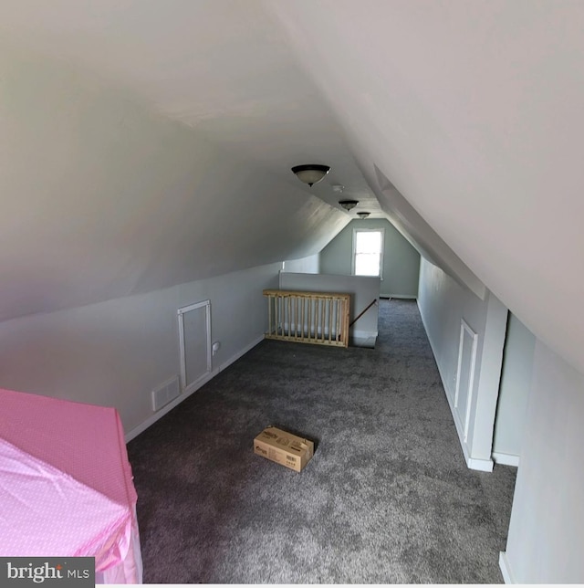 additional living space featuring dark carpet and vaulted ceiling