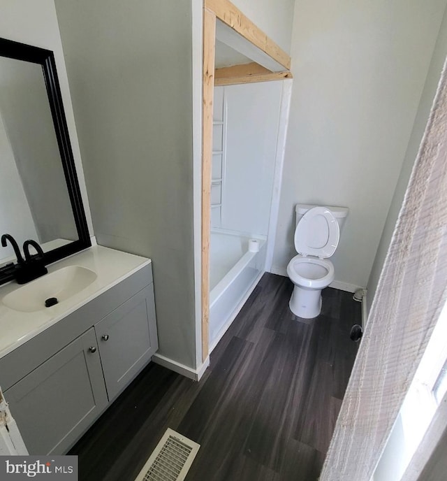 full bathroom with hardwood / wood-style floors, vanity, shower / bathtub combination, and toilet