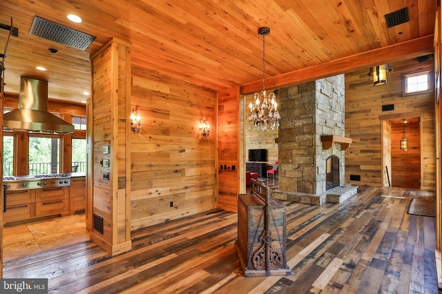 interior space with a fireplace, hardwood / wood-style floors, an inviting chandelier, and wood walls