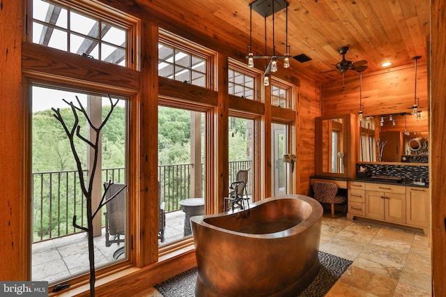 interior space featuring ceiling fan, wood ceiling, plenty of natural light, and wood walls