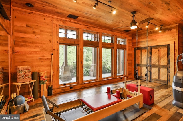 sunroom / solarium featuring plenty of natural light, ceiling fan, wooden ceiling, and rail lighting