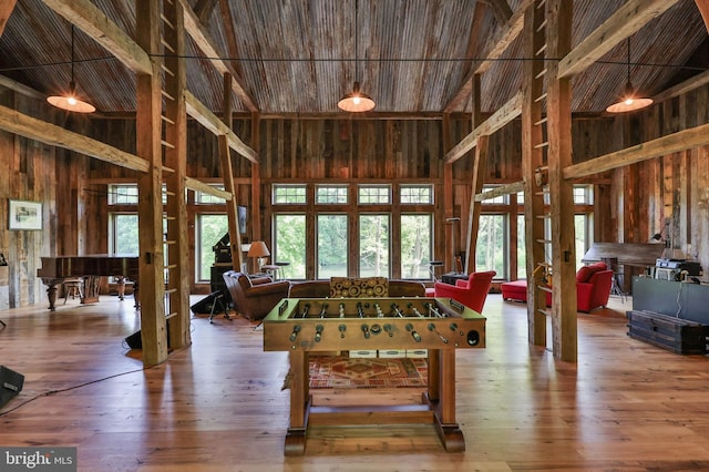 game room featuring hardwood / wood-style flooring, high vaulted ceiling, and wood walls