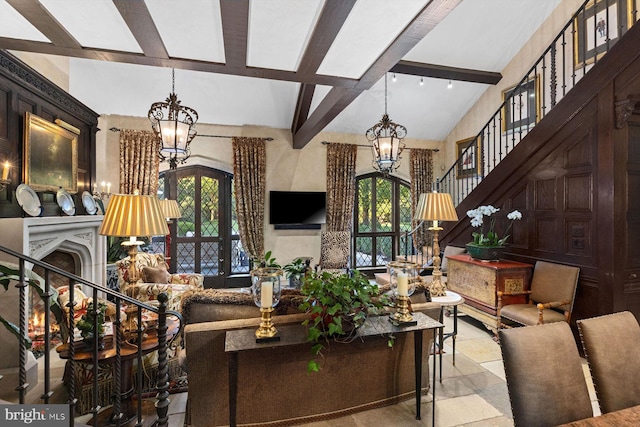 living room featuring lofted ceiling with beams, a wealth of natural light, and a notable chandelier