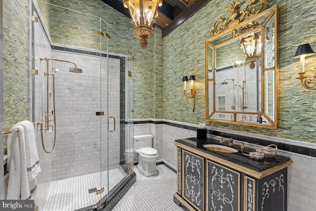 bathroom featuring vanity, toilet, a shower with shower door, and tile walls