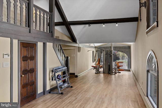 exercise room with hardwood / wood-style floors and high vaulted ceiling