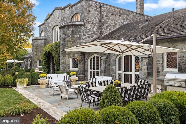 rear view of property with outdoor lounge area, a patio, and exterior kitchen