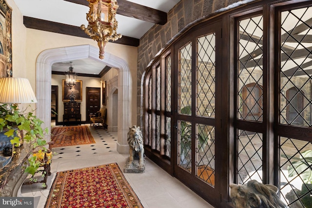 hall featuring beamed ceiling, light tile patterned flooring, and a chandelier