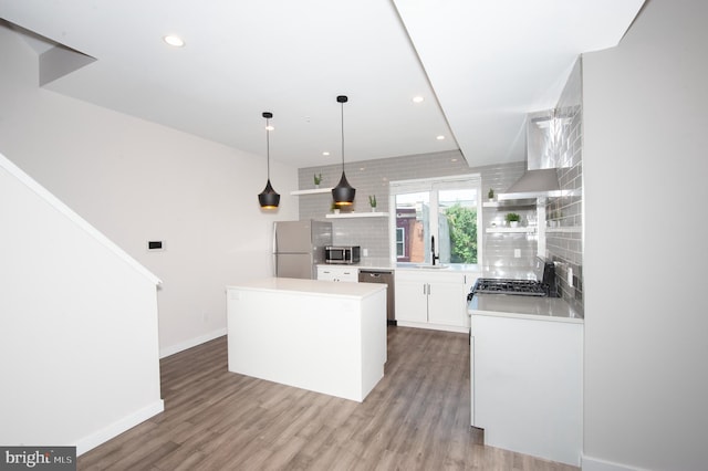 kitchen featuring a center island, hanging light fixtures, appliances with stainless steel finishes, tasteful backsplash, and white cabinetry