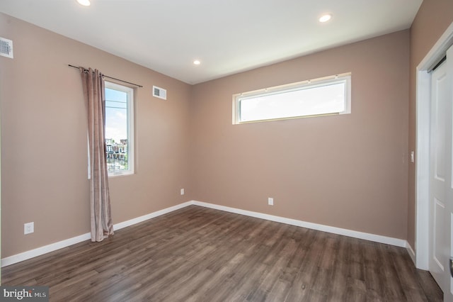 unfurnished room featuring plenty of natural light and dark hardwood / wood-style flooring