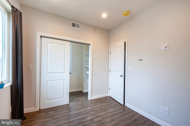 unfurnished bedroom with a closet and dark hardwood / wood-style floors