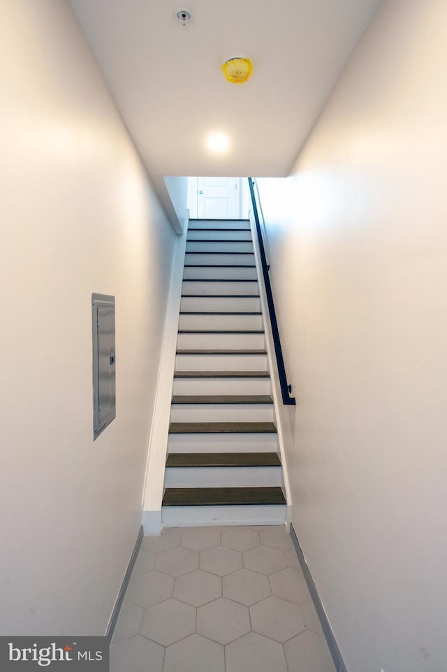 staircase with electric panel and tile patterned floors