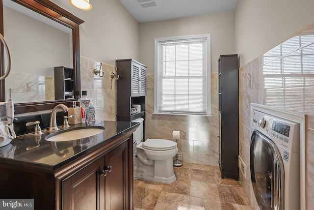 bathroom featuring vanity, toilet, tile walls, and washer / clothes dryer