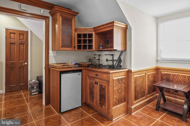 kitchen with dark tile patterned flooring, stainless steel fridge, and vaulted ceiling