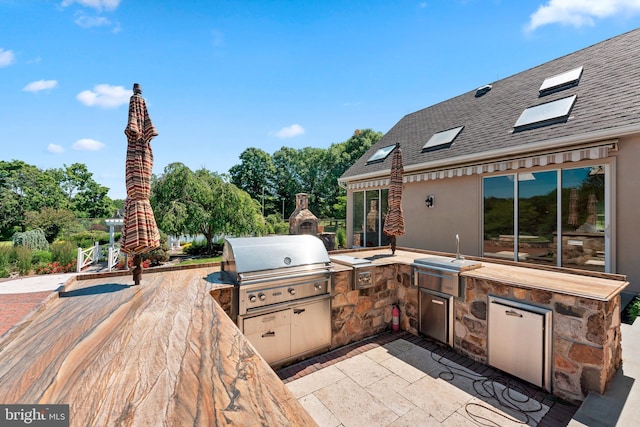 view of patio / terrace featuring a fireplace, an outdoor kitchen, and area for grilling