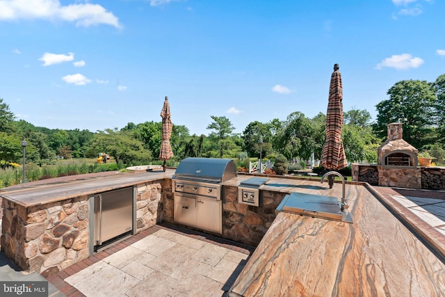 view of patio with area for grilling, an outdoor fireplace, and grilling area