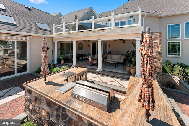 exterior space with an outdoor living space, ceiling fan, a balcony, and exterior kitchen