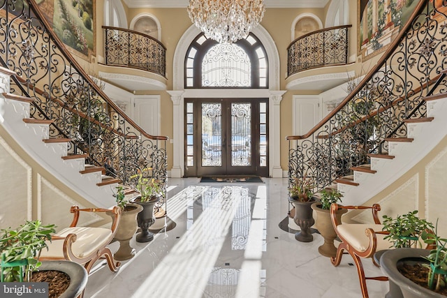 entrance foyer featuring an inviting chandelier, ornamental molding, a high ceiling, and french doors