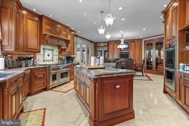 kitchen featuring french doors, hanging light fixtures, dark stone countertops, an island with sink, and appliances with stainless steel finishes