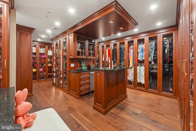 bar with hardwood / wood-style floors, crown molding, and dark stone counters