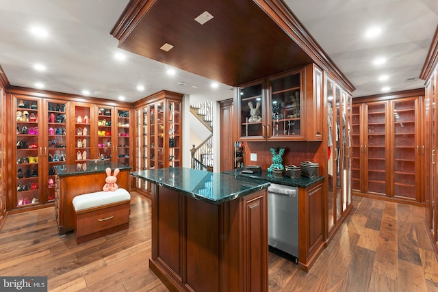 bar featuring ornamental molding, hardwood / wood-style flooring, stainless steel dishwasher, and dark stone counters