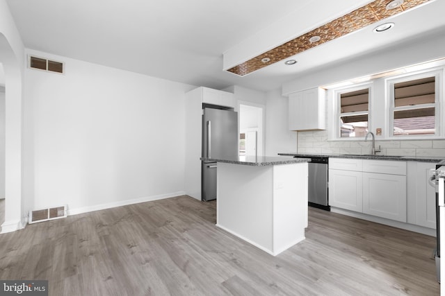 kitchen with appliances with stainless steel finishes, white cabinetry, a kitchen island, and sink