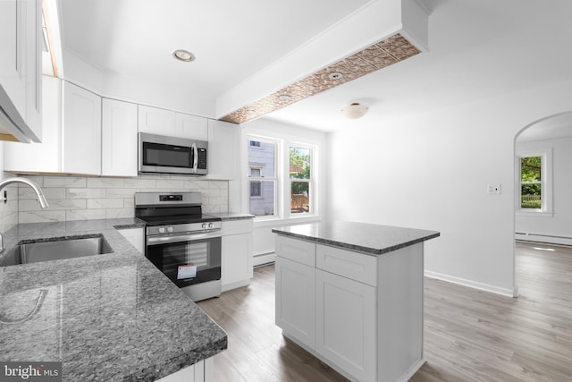 kitchen featuring stainless steel appliances, a kitchen island, white cabinetry, and sink