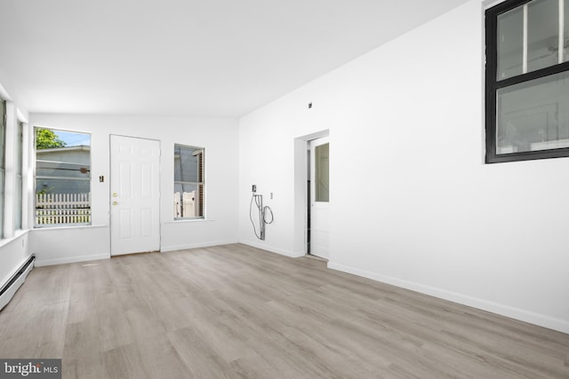 spare room with light wood-type flooring and vaulted ceiling