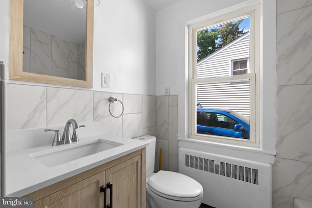 bathroom featuring radiator heating unit, vanity, tile walls, and toilet