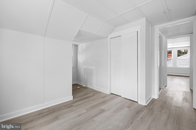 bonus room with light wood-type flooring and a baseboard heating unit