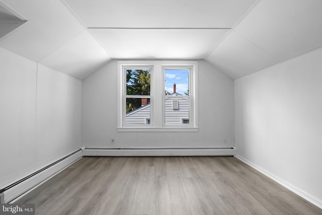 additional living space featuring baseboard heating, light hardwood / wood-style flooring, and lofted ceiling