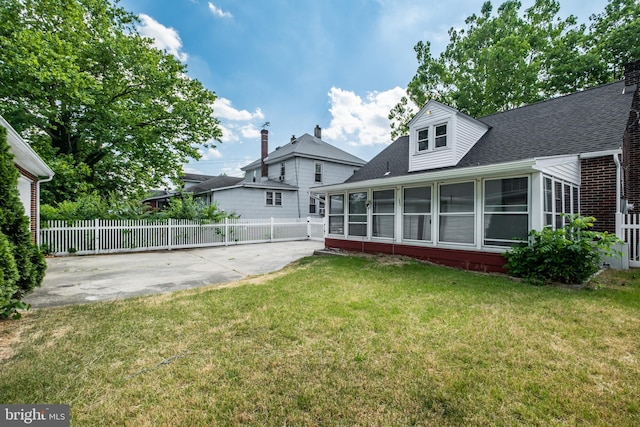 back of property with a lawn, a sunroom, and a patio