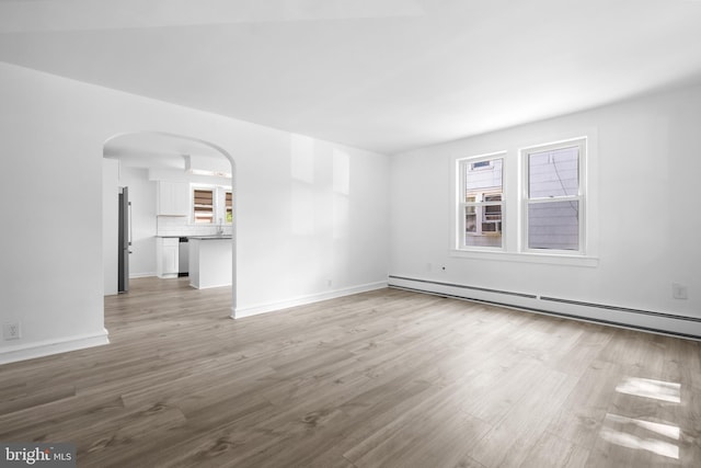 unfurnished room featuring baseboard heating and light hardwood / wood-style floors