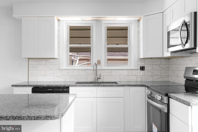 kitchen featuring decorative backsplash, white cabinetry, sink, and appliances with stainless steel finishes