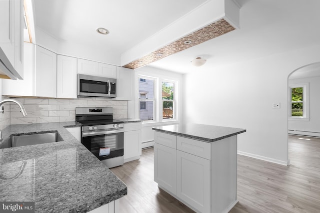 kitchen with appliances with stainless steel finishes, white cabinetry, a kitchen island, and sink