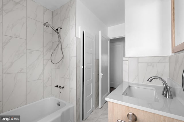 bathroom with tiled shower / bath, vanity, and tile walls