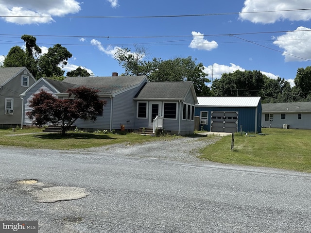 view of front of home with a front yard, an outdoor structure, and a garage