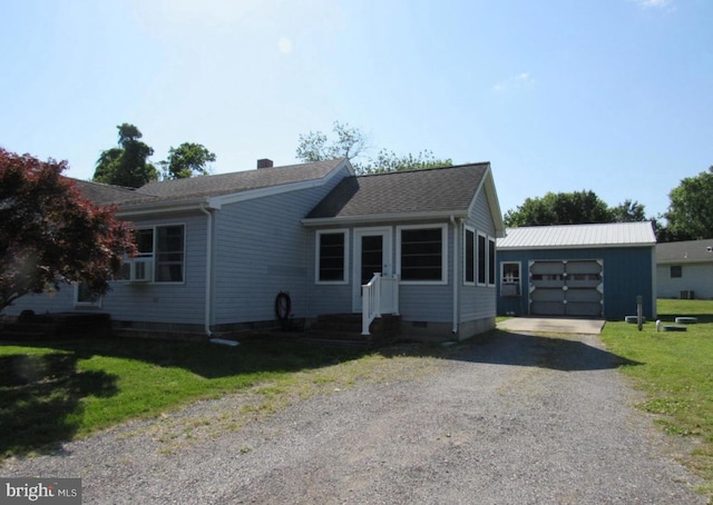 view of front of house featuring a garage, an outbuilding, and a front lawn